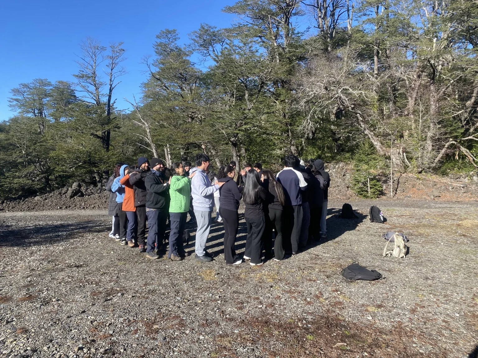 Grupo de participantes reunidos al aire libre visto desde cierta distancia